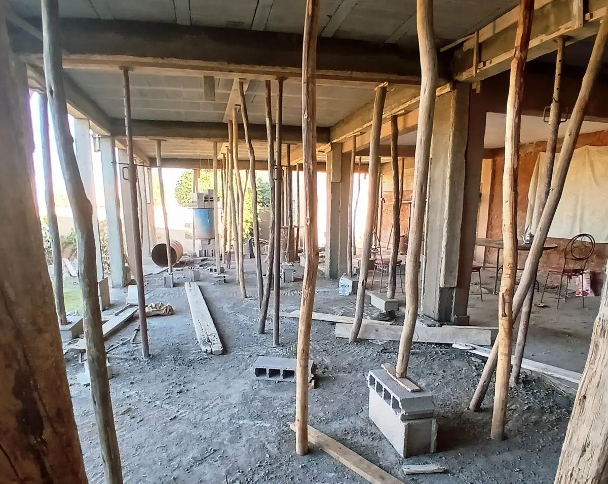 Une dalle de béton soutenue par de nombreux étais en bois, dans un volume encore ouvert.